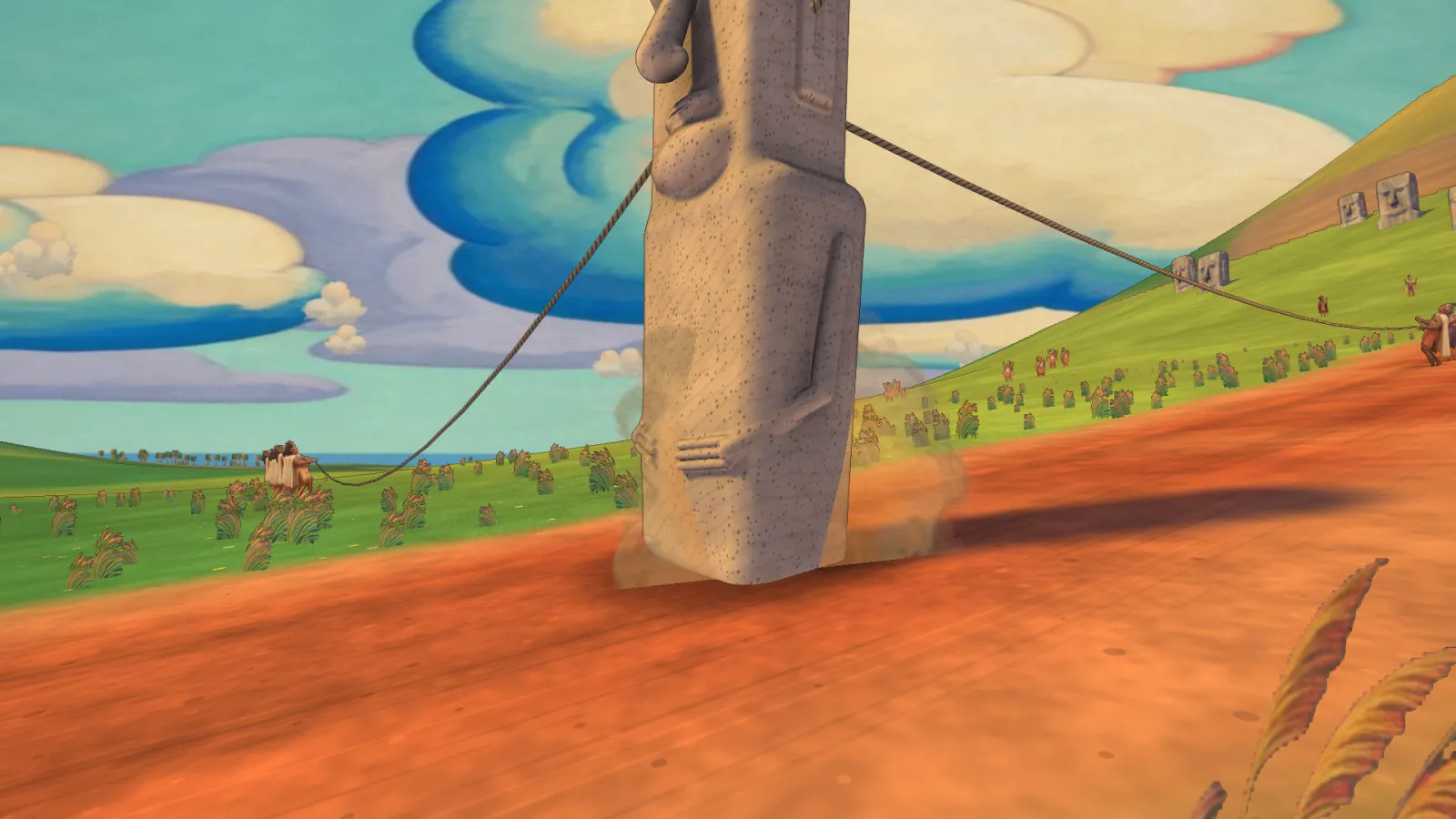 A tall stone moai is rocked along a red dirt road by ropes beneath fresco clouds.